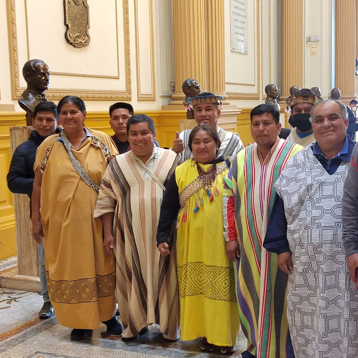 Group of people in traditional attire posing for a photo in an indoor setting with decorative elements.